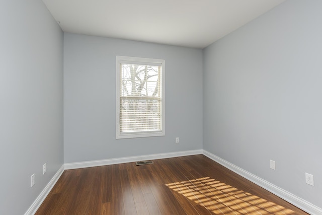 unfurnished room with dark wood-style floors, baseboards, and visible vents