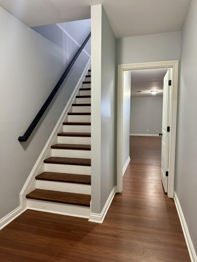 staircase featuring baseboards and wood finished floors