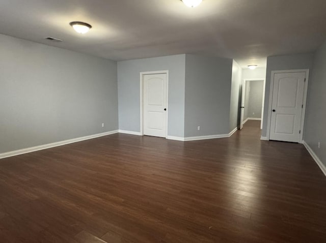 spare room with baseboards, dark wood-style floors, and visible vents