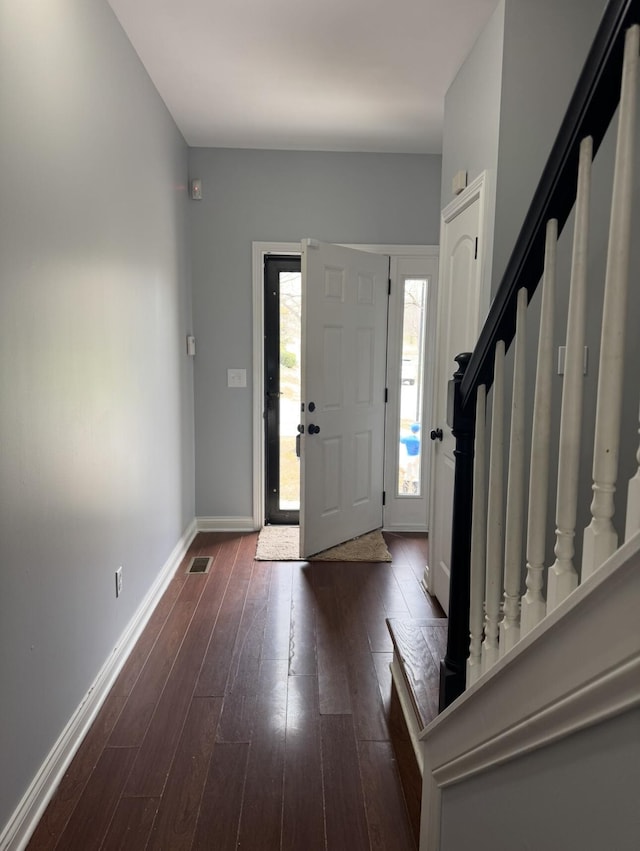 entrance foyer featuring visible vents, baseboards, stairs, and dark wood finished floors