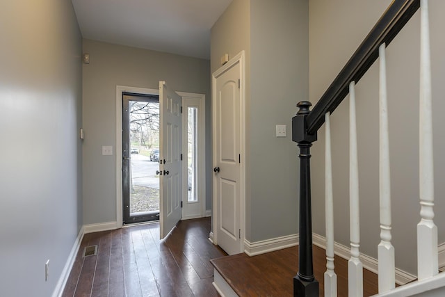 foyer entrance with stairs, dark wood-style floors, baseboards, and visible vents