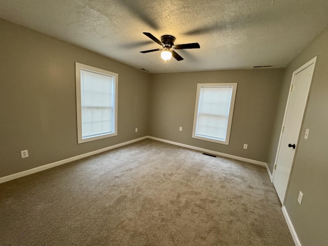 carpeted empty room with ceiling fan and a textured ceiling