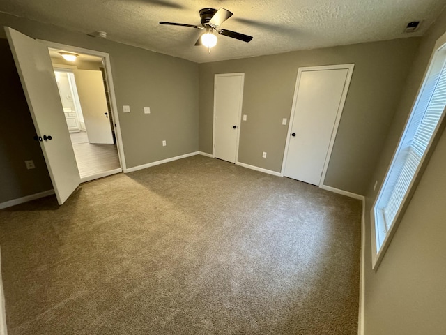 unfurnished bedroom featuring a textured ceiling, carpet floors, and ceiling fan