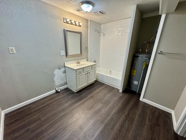 bathroom with a textured ceiling, electric water heater, hardwood / wood-style flooring, and tiled shower / bath