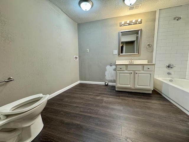 full bathroom with wood-type flooring, a textured ceiling, toilet, vanity, and tiled shower / bath