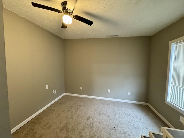 spare room featuring ceiling fan, carpet floors, and a textured ceiling