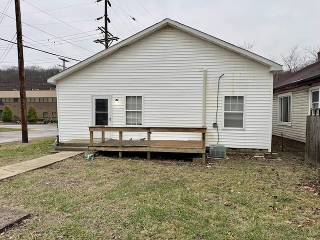 rear view of property featuring a wooden deck and a lawn