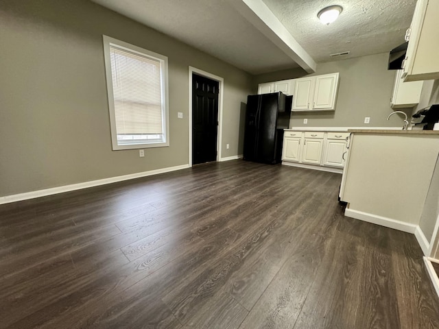 kitchen featuring white cabinets, black fridge, a textured ceiling, and dark wood-type flooring