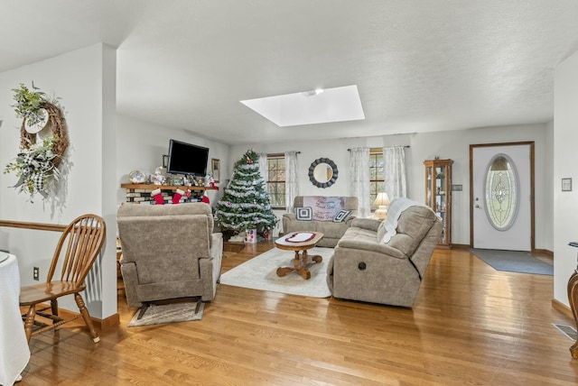 living room featuring hardwood / wood-style floors, a textured ceiling, and a skylight