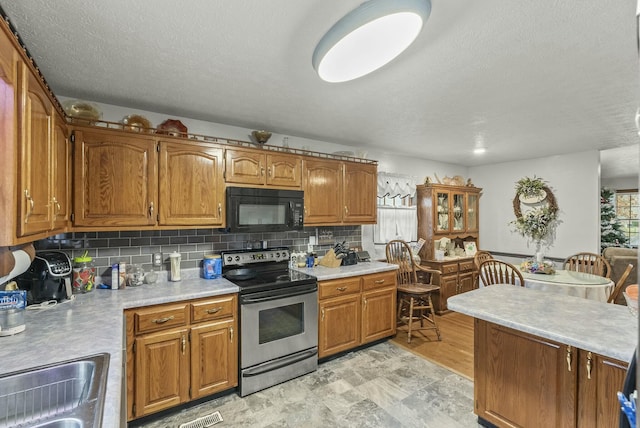 kitchen featuring decorative backsplash, sink, and stainless steel range with electric cooktop