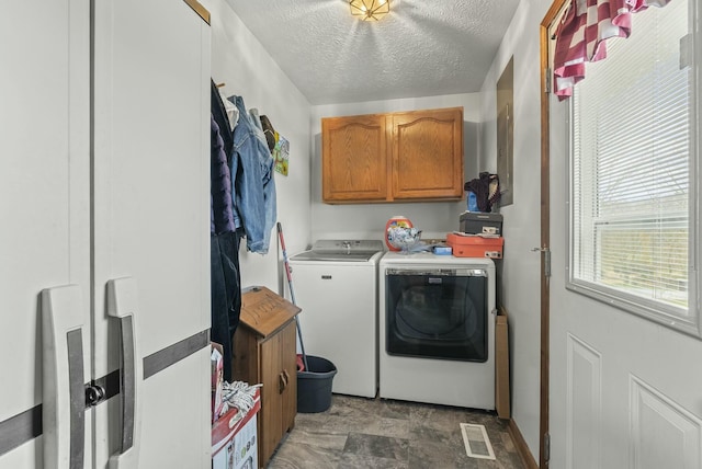 laundry area with cabinets, washing machine and dryer, and a textured ceiling