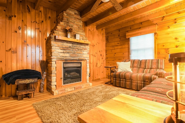 living room featuring wood walls, light hardwood / wood-style flooring, a fireplace, beamed ceiling, and wood ceiling