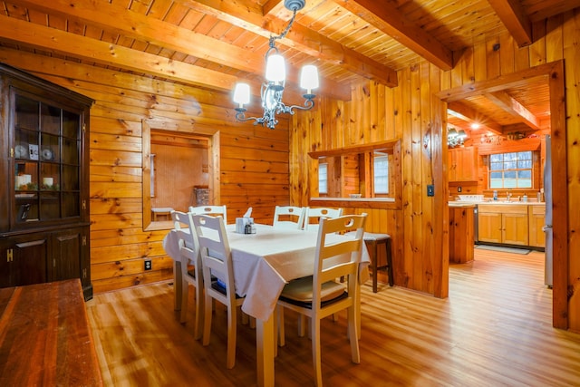 dining area featuring beamed ceiling, light hardwood / wood-style floors, wooden ceiling, and a chandelier