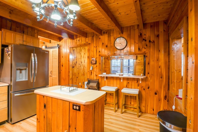 kitchen with beamed ceiling, wood ceiling, stainless steel refrigerator with ice dispenser, and wooden walls