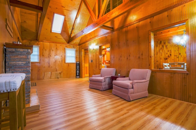 living room with wooden walls, light hardwood / wood-style floors, and high vaulted ceiling