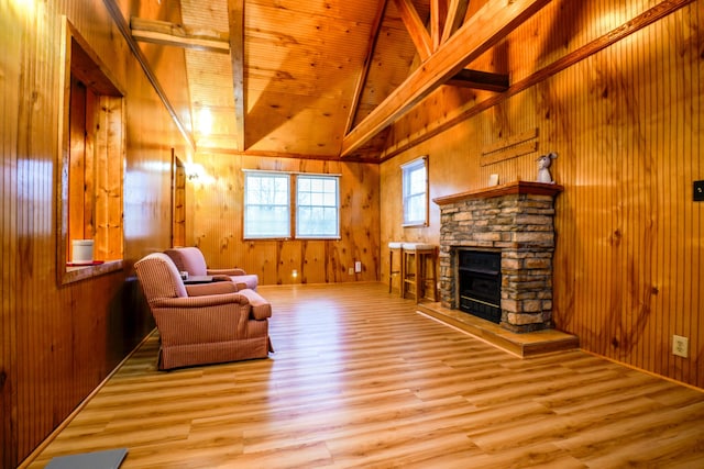 sitting room featuring light hardwood / wood-style floors, a stone fireplace, wood walls, and wood ceiling