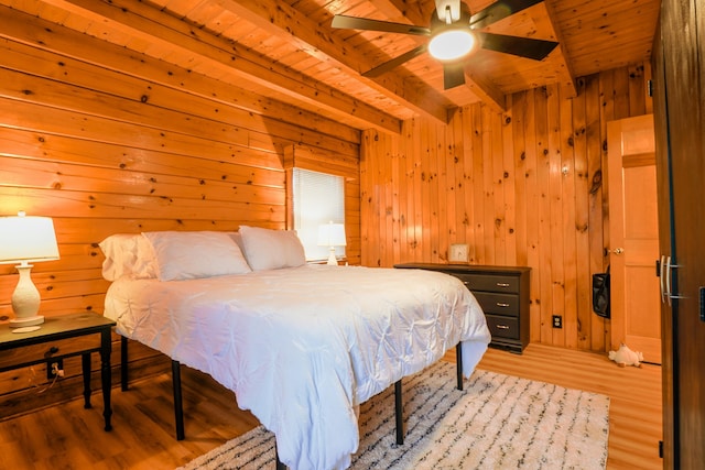 bedroom with light wood-type flooring, wood ceiling, ceiling fan, wooden walls, and beam ceiling