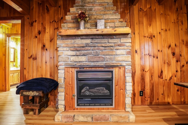 details with hardwood / wood-style floors, a stone fireplace, and wooden walls