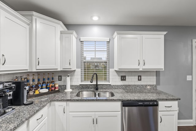 kitchen featuring stainless steel dishwasher, dark stone countertops, white cabinets, and sink