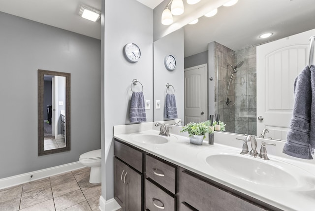 bathroom with tile patterned floors, vanity, a tile shower, and toilet