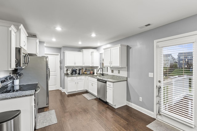 kitchen featuring tasteful backsplash, dark hardwood / wood-style floors, dark stone counters, white cabinets, and appliances with stainless steel finishes