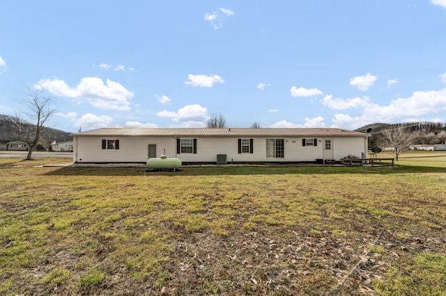 back of house featuring central AC unit and a lawn