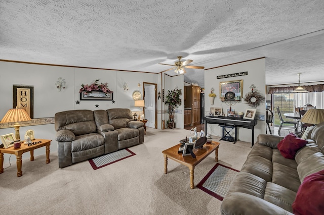 living room featuring a textured ceiling, ceiling fan, ornamental molding, and light carpet