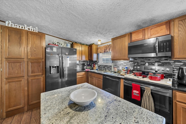 kitchen featuring backsplash, light stone countertops, sink, and stainless steel appliances