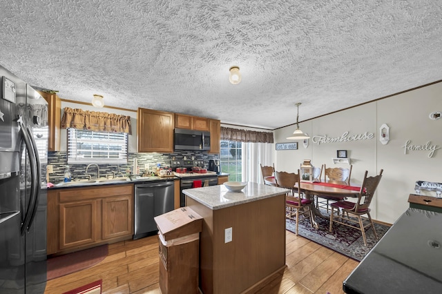 kitchen featuring a center island, sink, hanging light fixtures, light hardwood / wood-style flooring, and appliances with stainless steel finishes