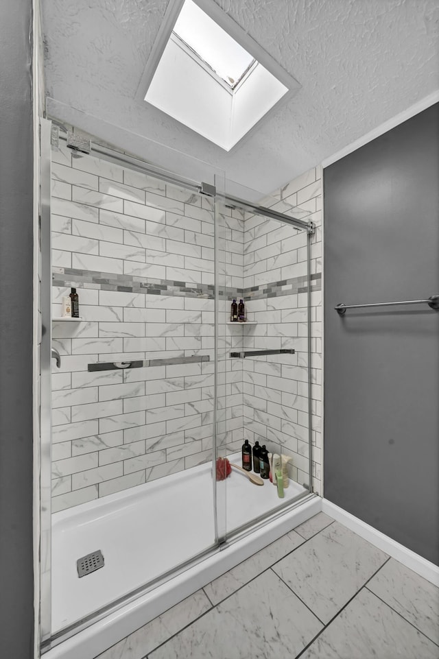 bathroom featuring a textured ceiling, a skylight, and a shower with door