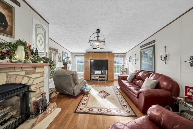 living room with a textured ceiling, ornamental molding, a fireplace, and light hardwood / wood-style flooring