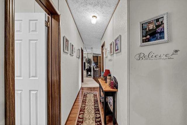 hall featuring a textured ceiling and light hardwood / wood-style flooring