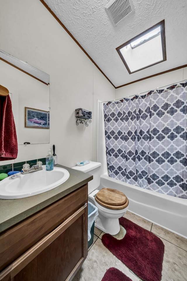 bathroom with vanity, lofted ceiling with skylight, tile patterned flooring, toilet, and a textured ceiling