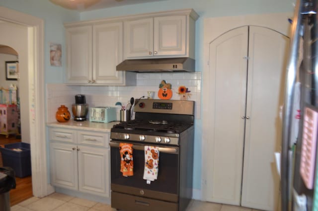 kitchen featuring gas stove, tasteful backsplash, cream cabinets, and light tile patterned floors