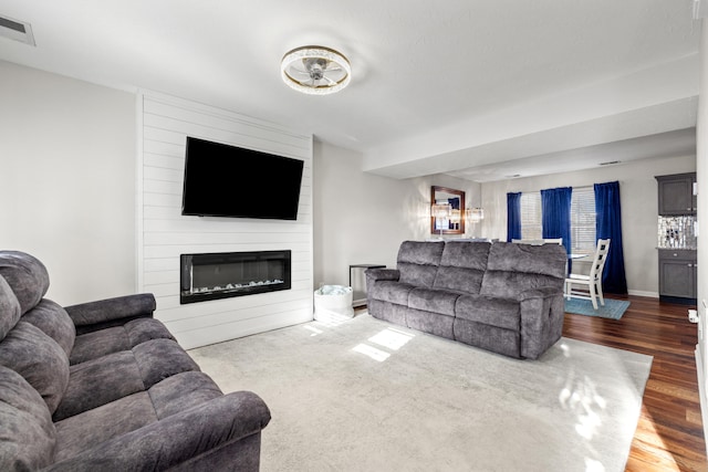 living room with a large fireplace and dark wood-type flooring