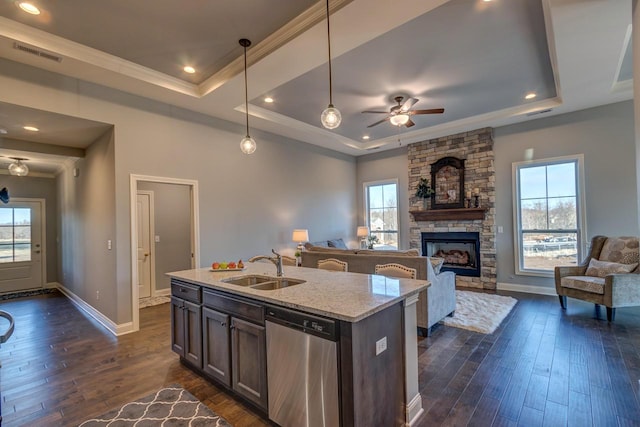 kitchen featuring pendant lighting, sink, stainless steel dishwasher, light stone countertops, and a tray ceiling