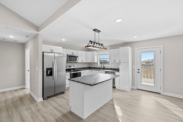 kitchen featuring pendant lighting, a kitchen island, white cabinetry, and appliances with stainless steel finishes