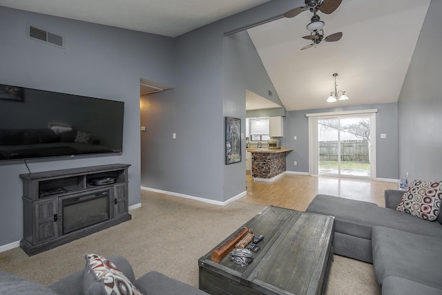 living room with ceiling fan with notable chandelier, lofted ceiling, and light carpet