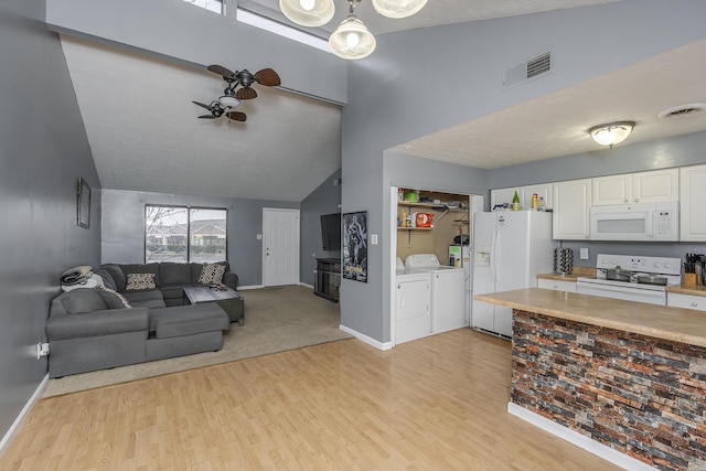 living room featuring ceiling fan, washer and clothes dryer, vaulted ceiling, and light hardwood / wood-style flooring