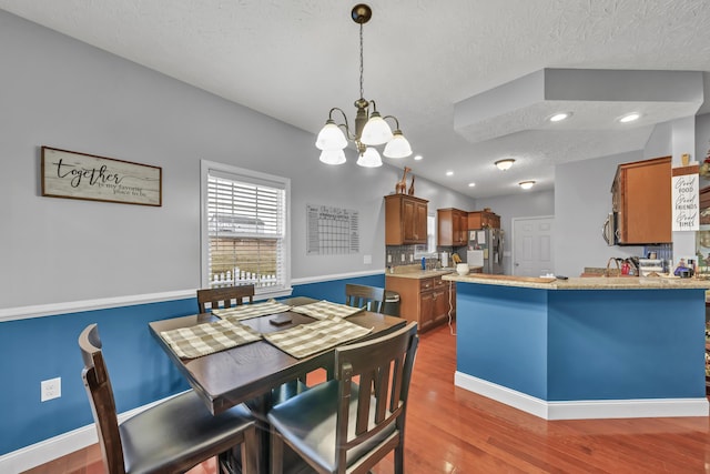 dining space featuring hardwood / wood-style floors, a textured ceiling, an inviting chandelier, and sink