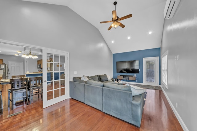 living room with hardwood / wood-style floors, ceiling fan with notable chandelier, high vaulted ceiling, and a wall unit AC