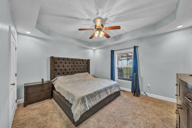 carpeted bedroom featuring a raised ceiling, ceiling fan, and a textured ceiling