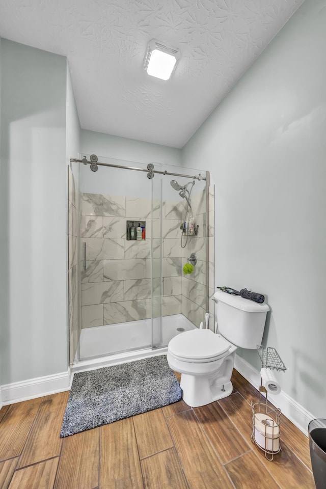 bathroom with an enclosed shower, toilet, and a textured ceiling