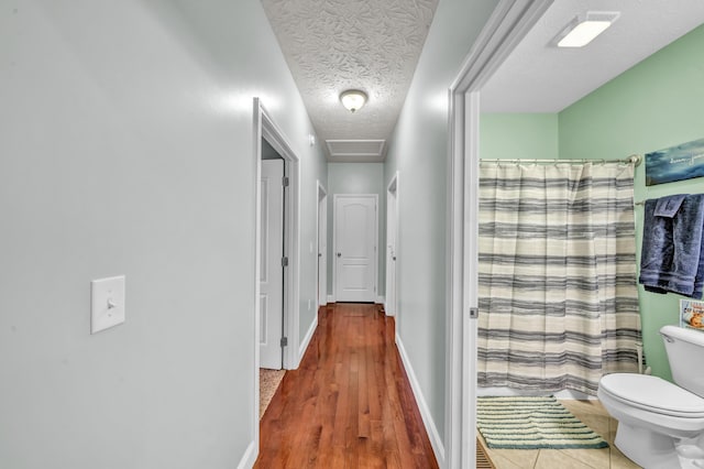 hallway with a textured ceiling and hardwood / wood-style flooring