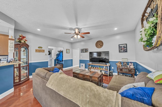 living room with a textured ceiling, hardwood / wood-style flooring, and ceiling fan