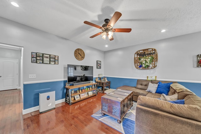 living room featuring ceiling fan, wood-type flooring, and a textured ceiling