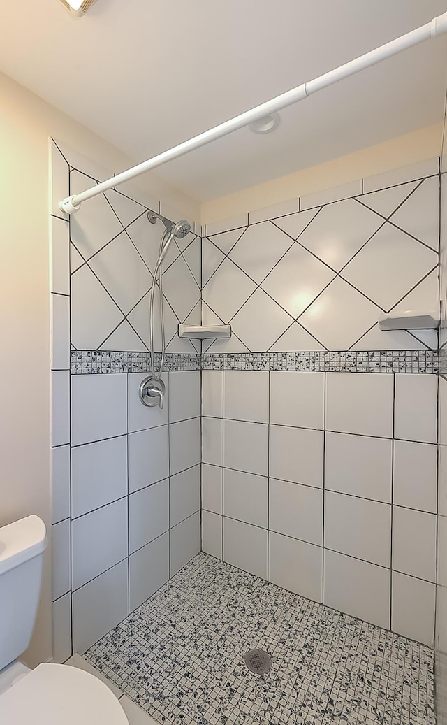 bathroom featuring a tile shower and toilet