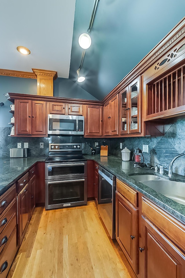 kitchen featuring track lighting, tasteful backsplash, stainless steel appliances, sink, and light hardwood / wood-style flooring