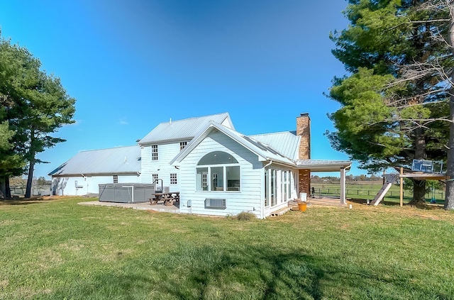 rear view of house featuring a yard and a hot tub