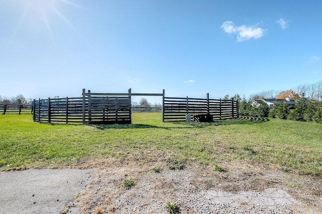 view of gate with a lawn and a rural view